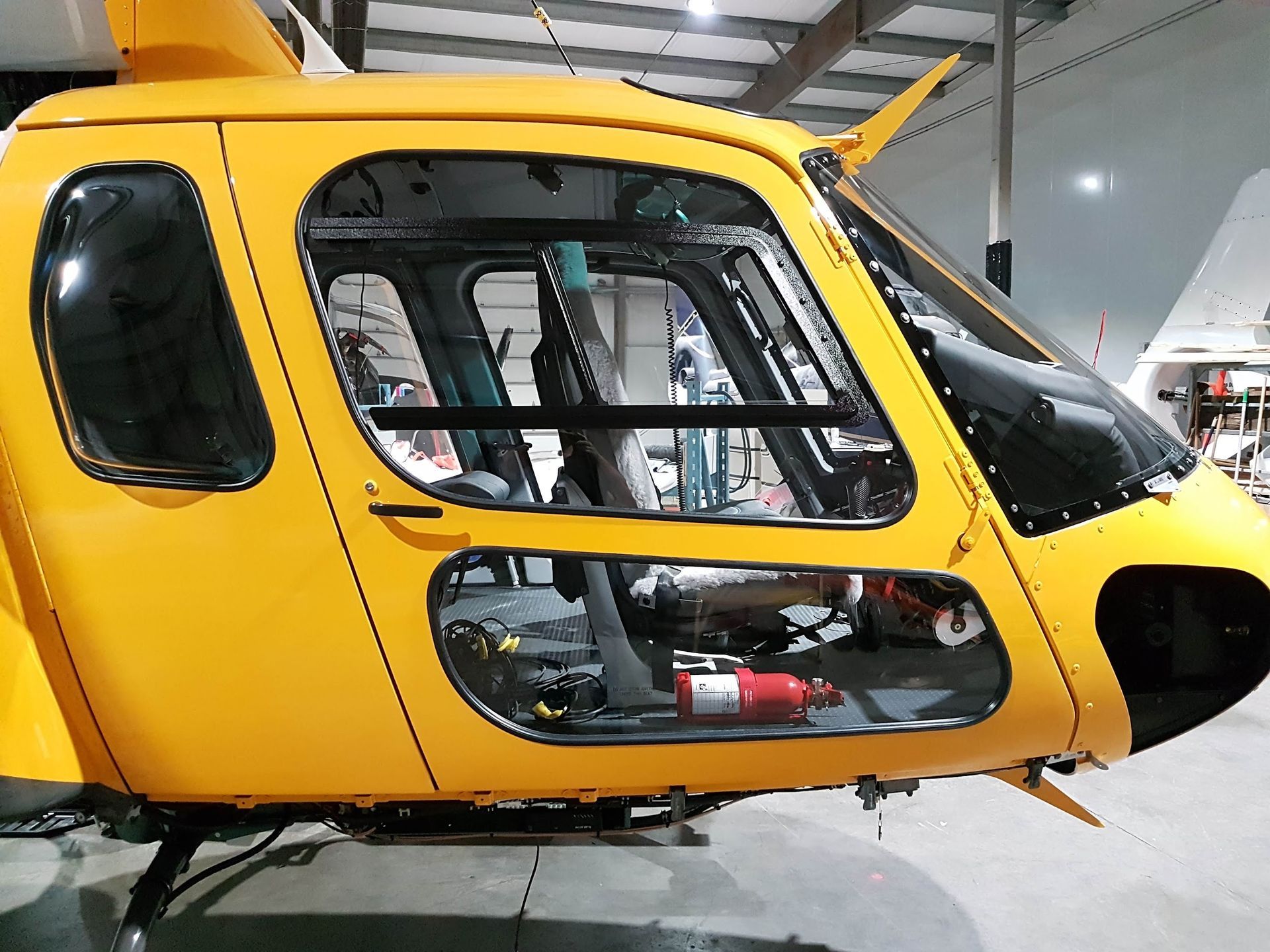 Yellow helicopter cockpit with glass windows, parked inside a hangar.