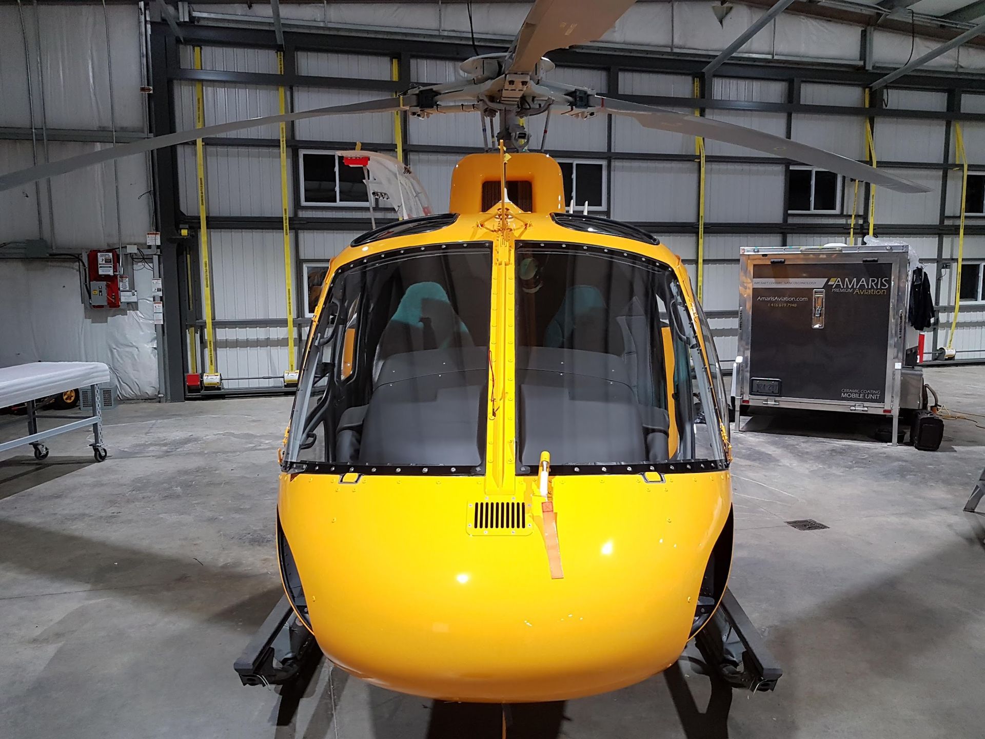 Yellow helicopter inside a hangar, viewed head-on.