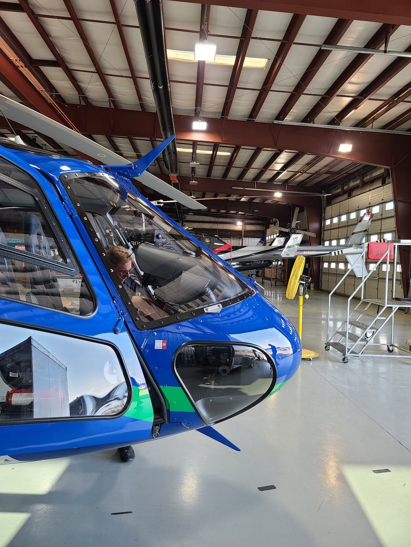 Blue and green helicopter in a hangar.