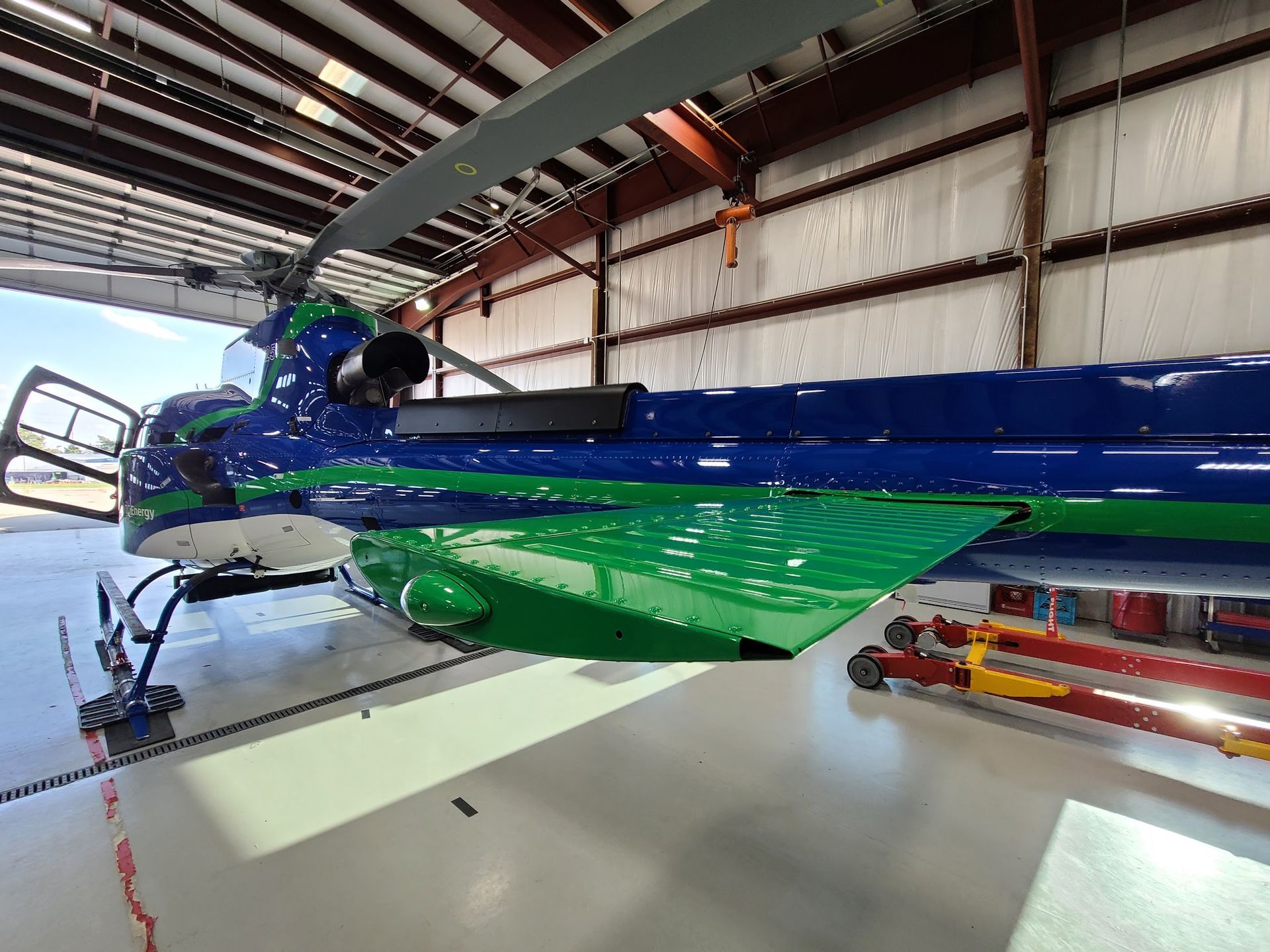 Blue and green helicopter in a hangar.
