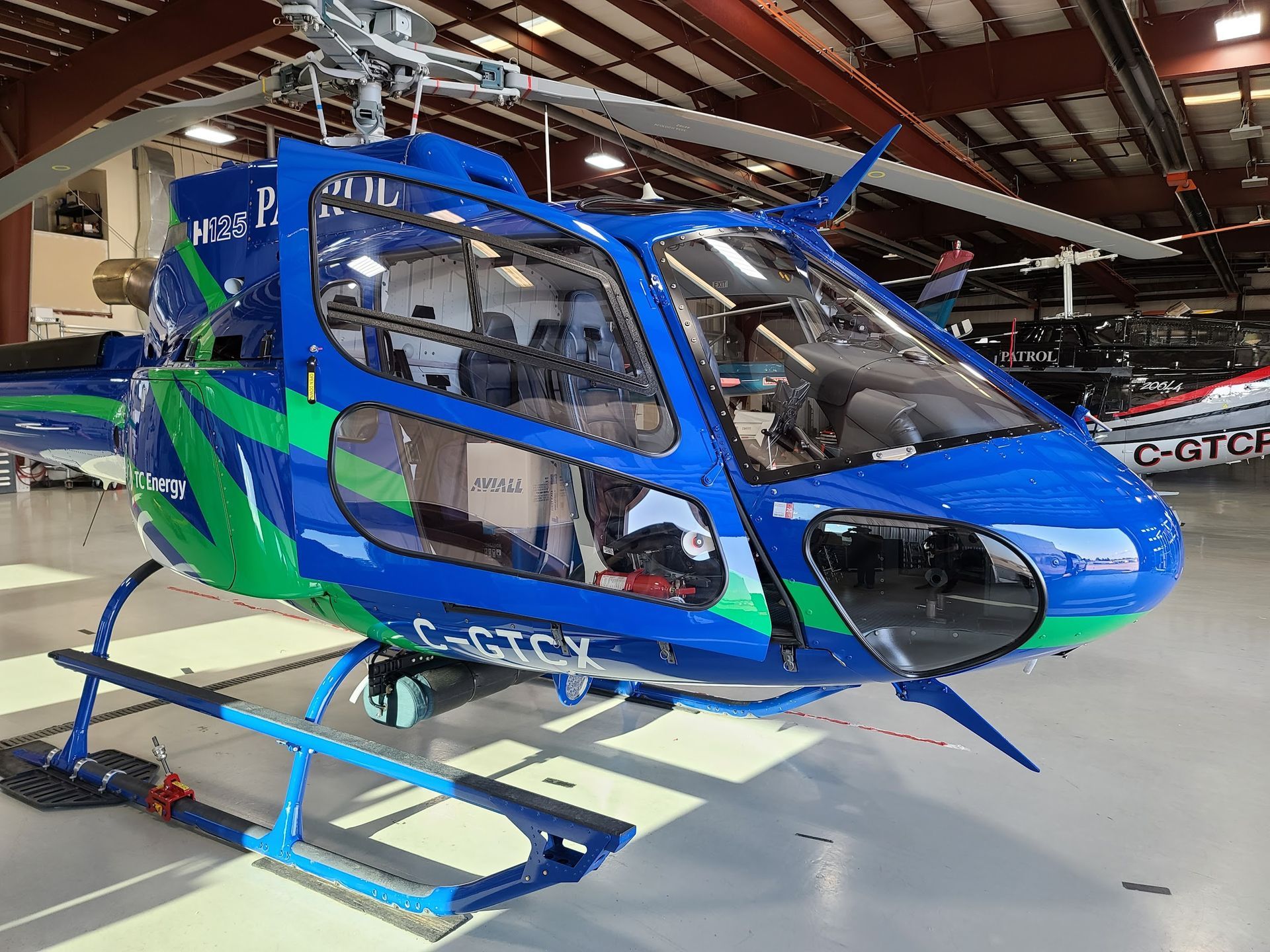 Blue and green helicopter in a hangar, with