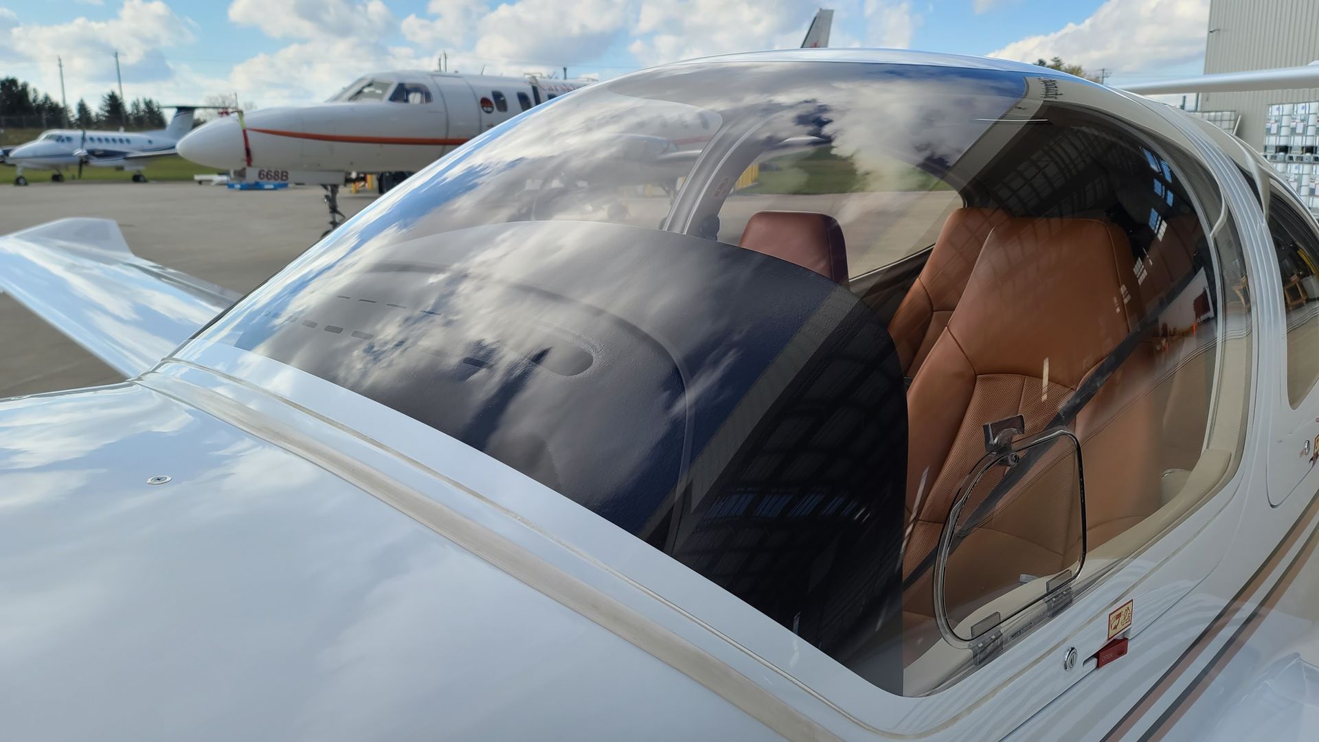 White airplane cockpit with tan seats, view of a second plane behind it.