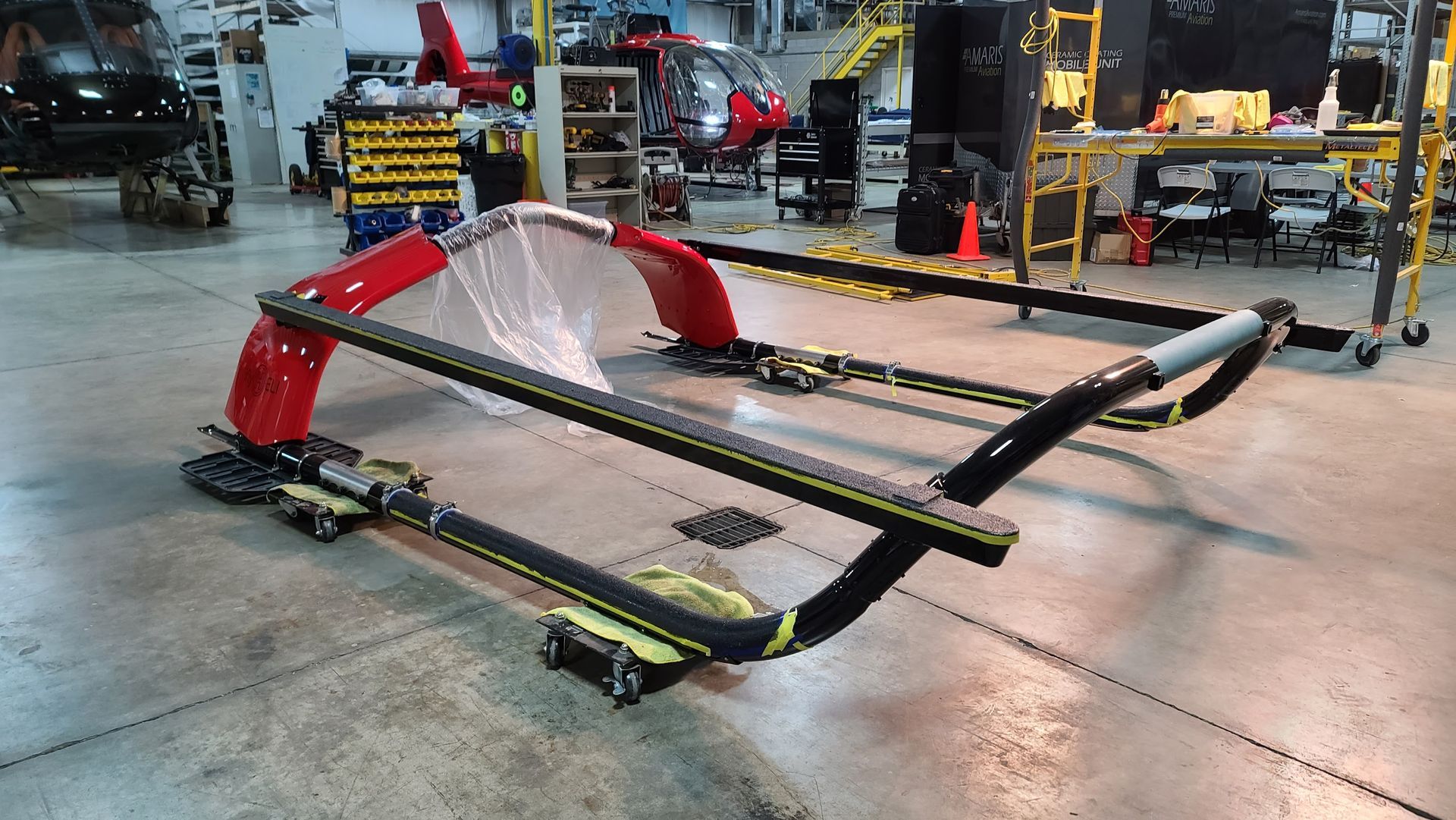 Red and black aircraft frame on a hangar floor, likely for repair or assembly.