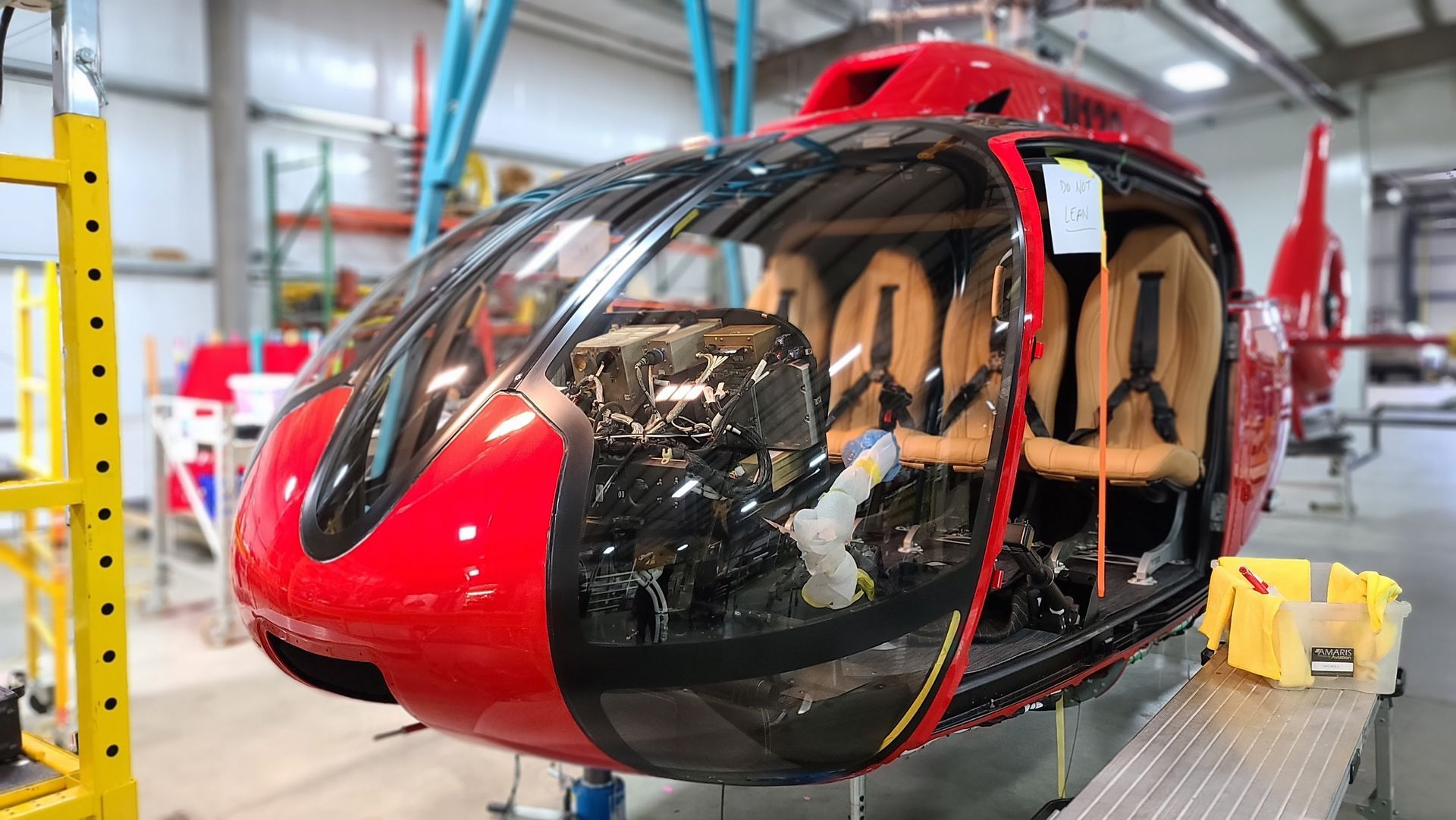 Red helicopter cabin in a workshop, interior view with seats visible.
