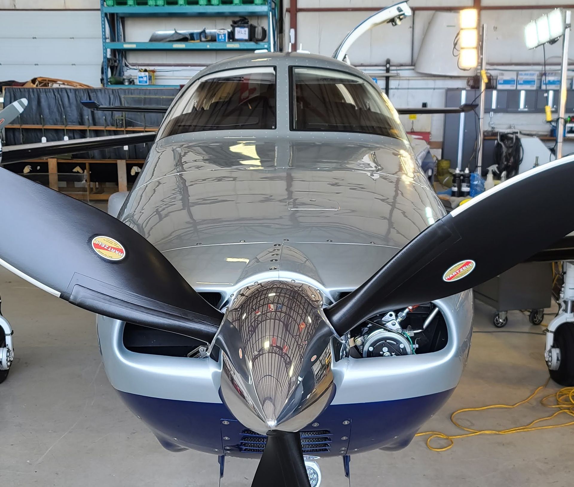 Silver and blue airplane with propeller, in a hangar.