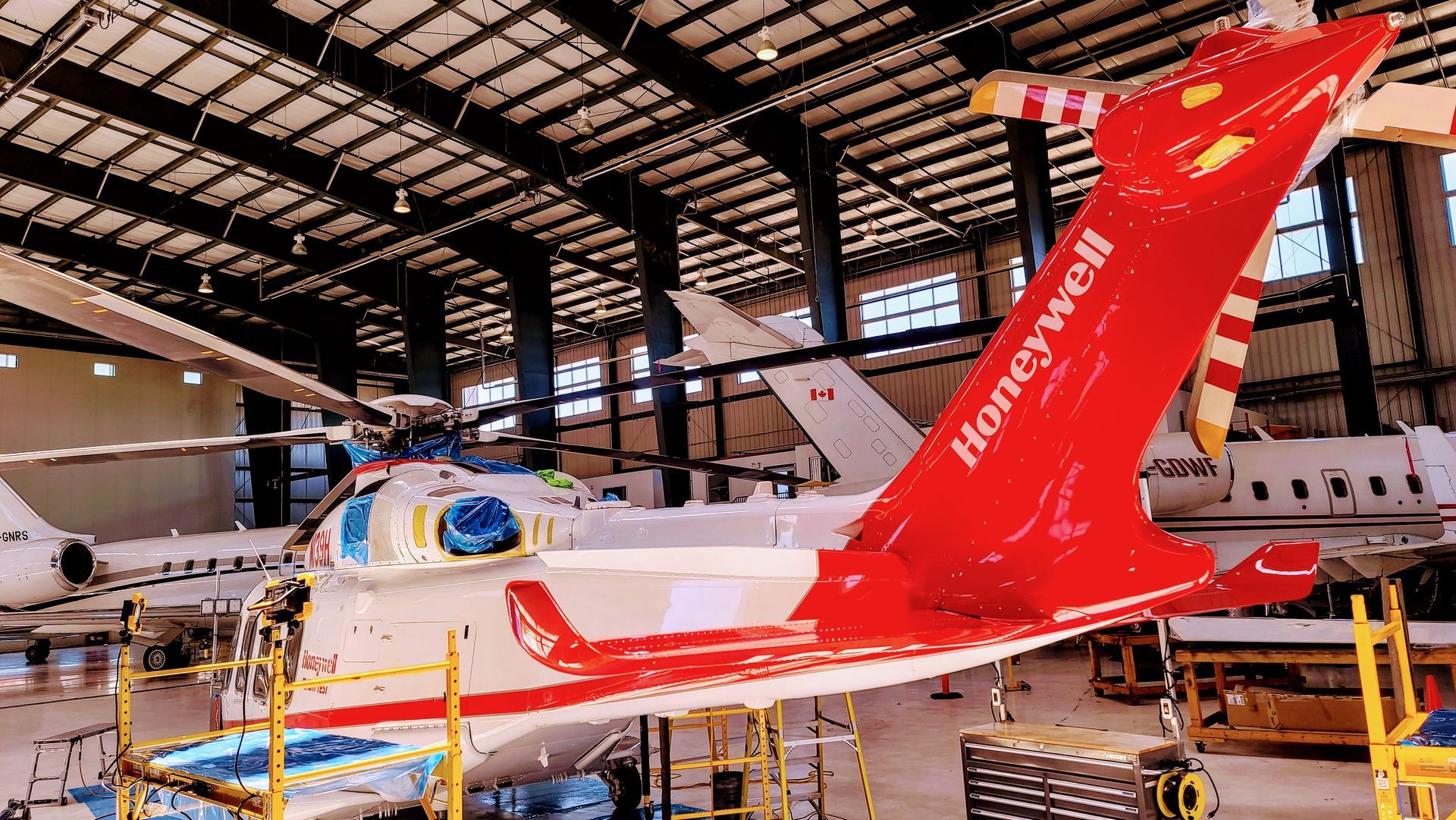 Helicopter in a hangar with a red Honeywell tail. White and red color scheme.