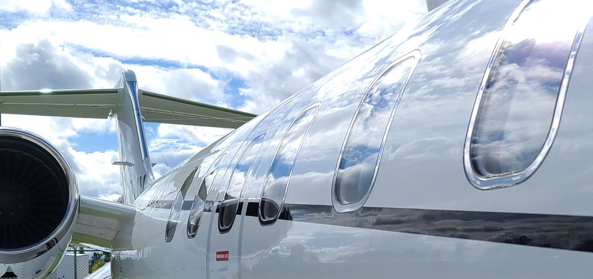 Airplane wing with reflective winglets, sky reflecting in the winglets, plane sits on the runway.
