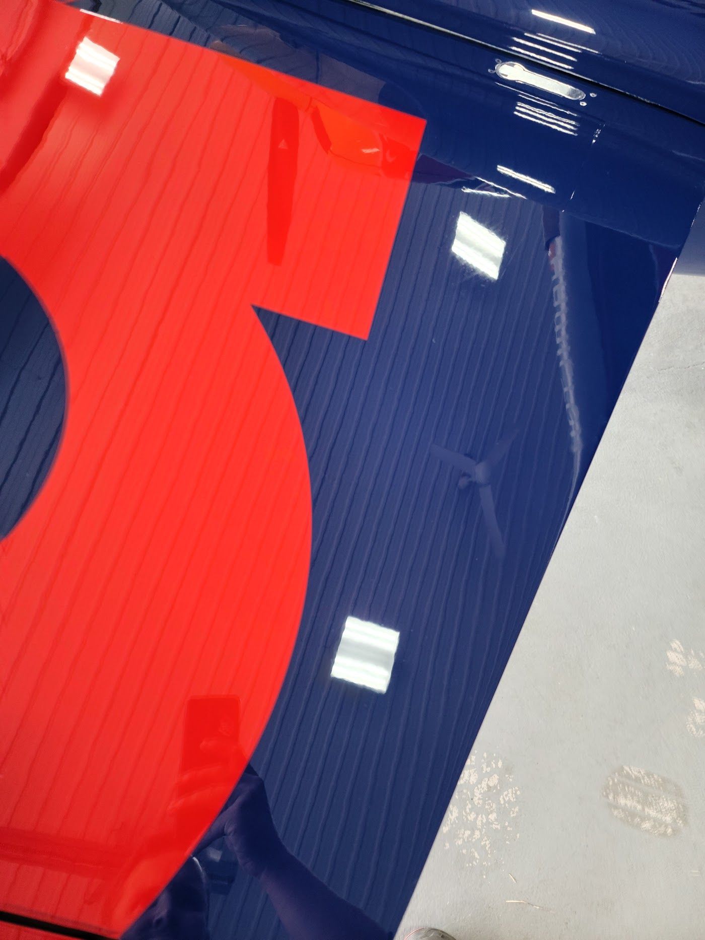 Red number 3 on a blue aircraft wing, reflecting square lights.