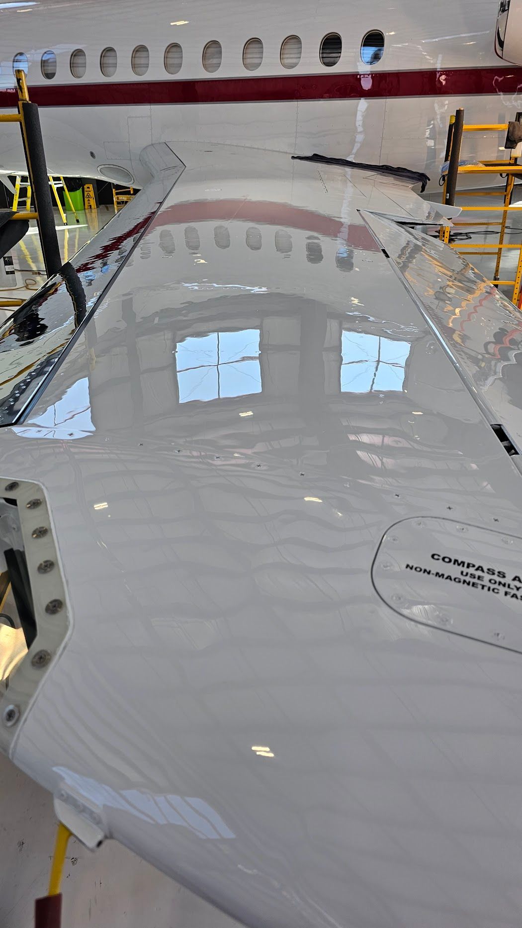 Airplane wing, white and maroon, reflecting a window.