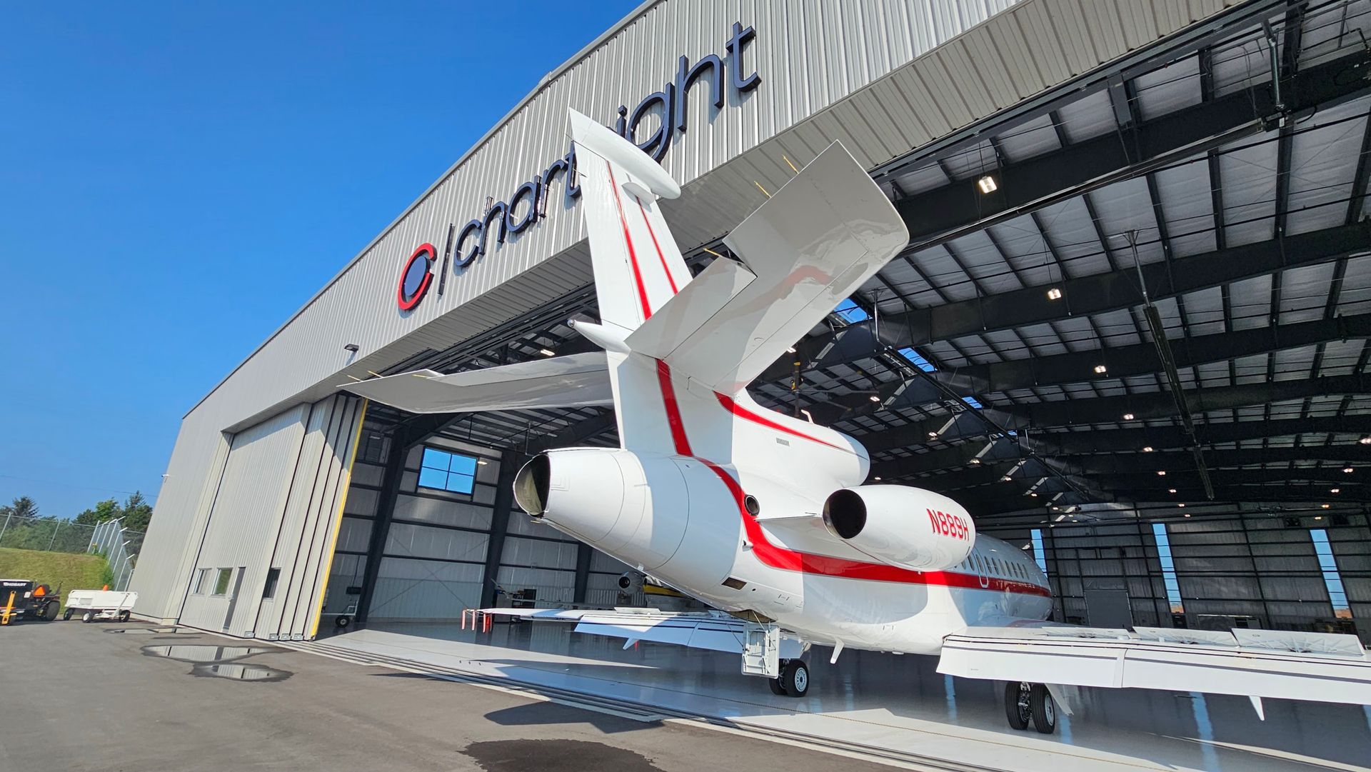 White and red private jet exiting a hangar with