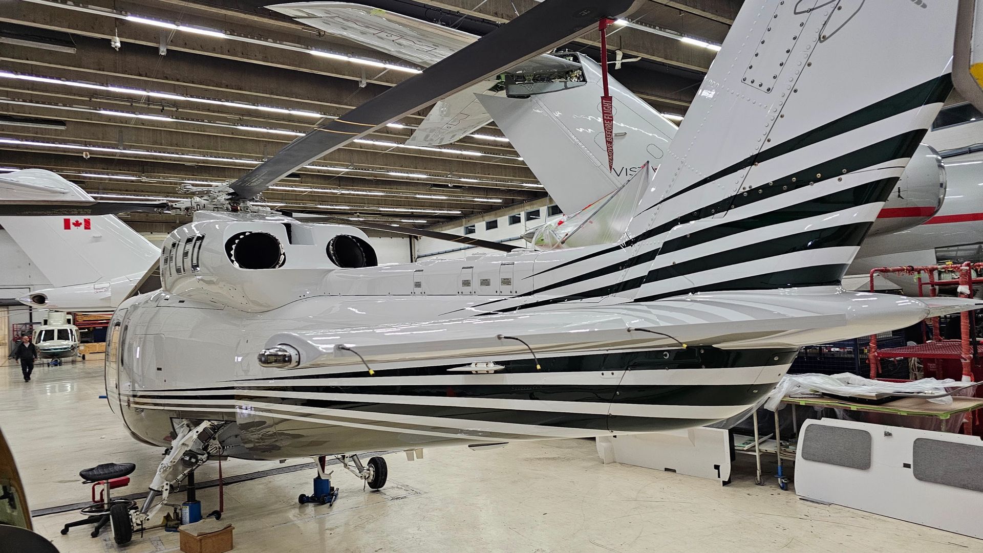 White helicopter with green stripes, in a hangar.