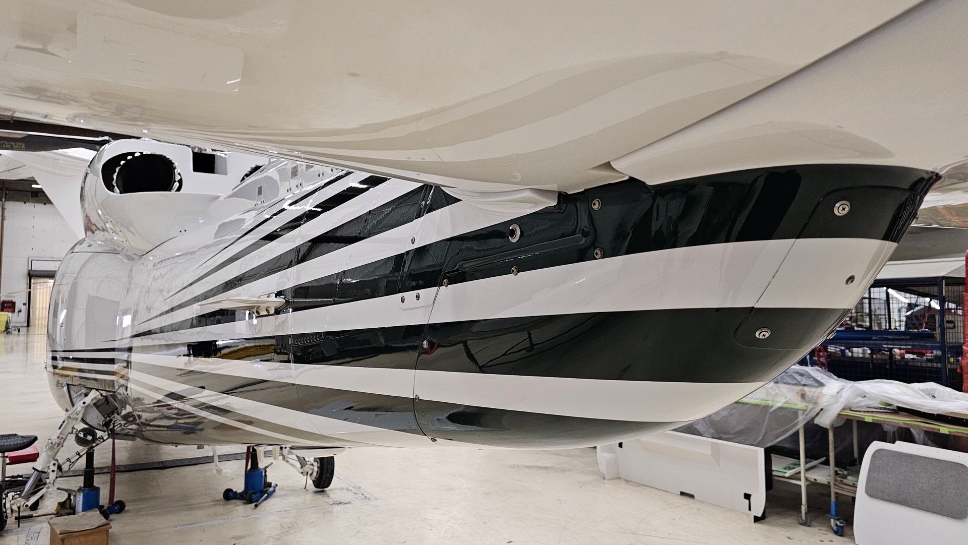 White and black airplane wing underside in a hangar.