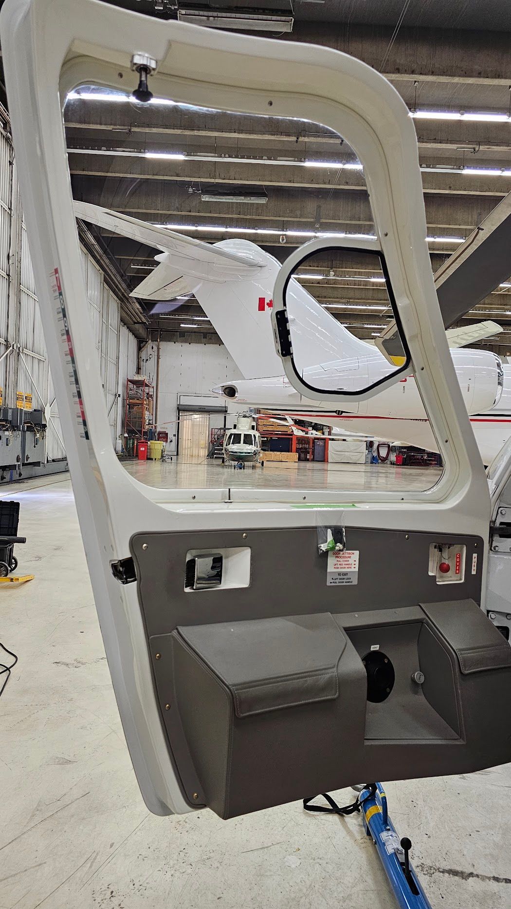 Open aircraft door showing the tail and interior of a hangar.