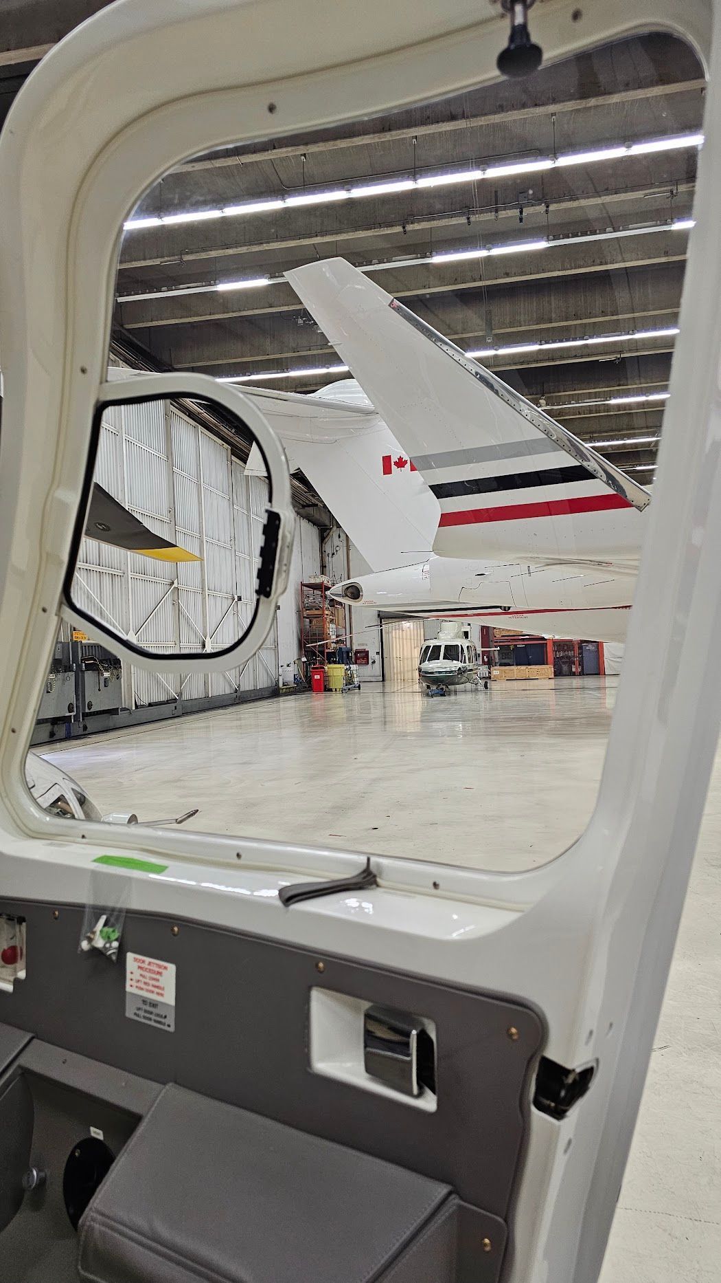 View from an aircraft door, showing another aircraft inside a hangar.
