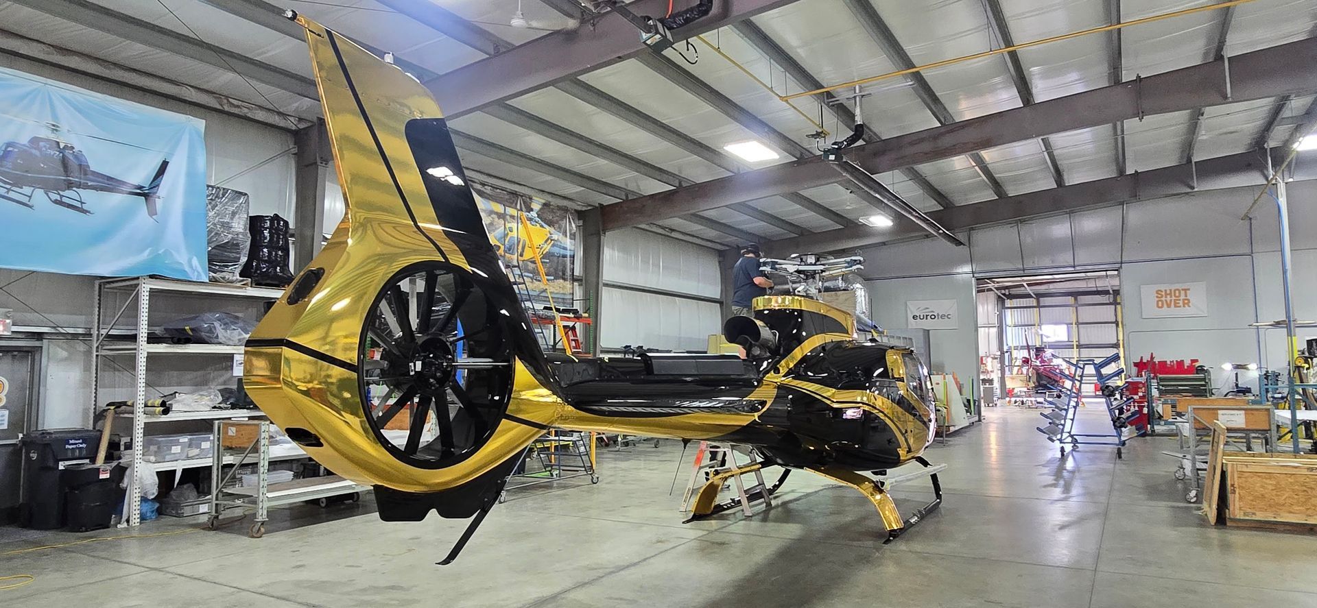 A gold and black helicopter inside a large hangar.