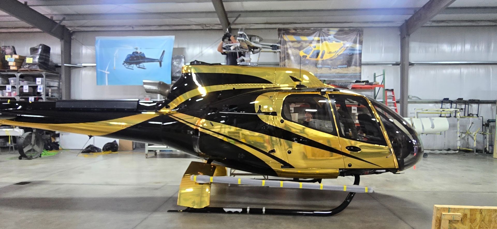 A black and gold helicopter in a hangar.