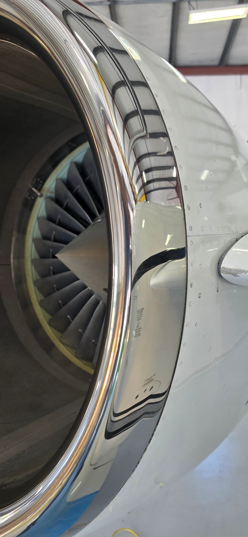 Close-up view of a jet engine's front fan and outer casing, showing reflective metal surfaces.
