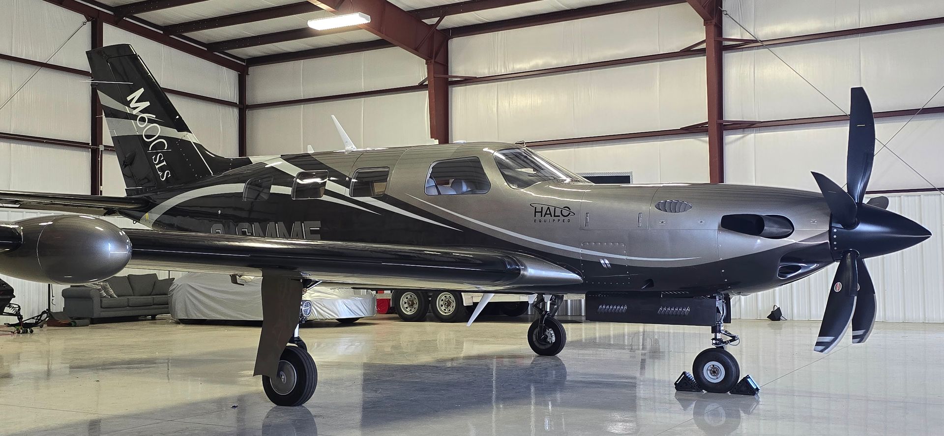 A silver and black Pilatus PC-12 airplane inside a hangar.