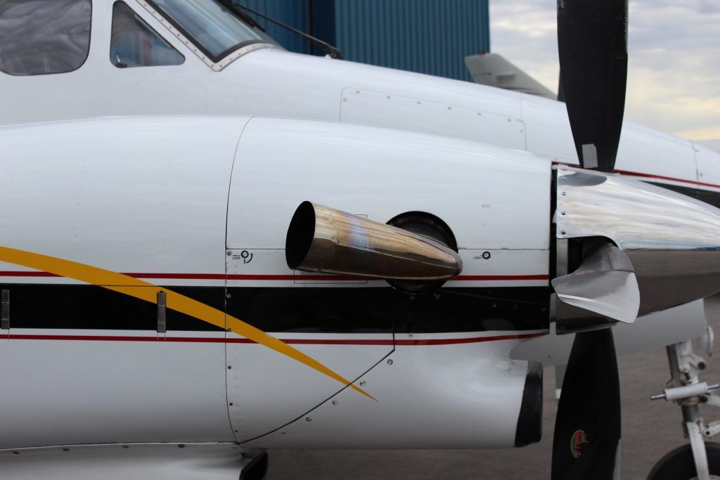 Close-up of a white airplane engine with a damaged exhaust port.