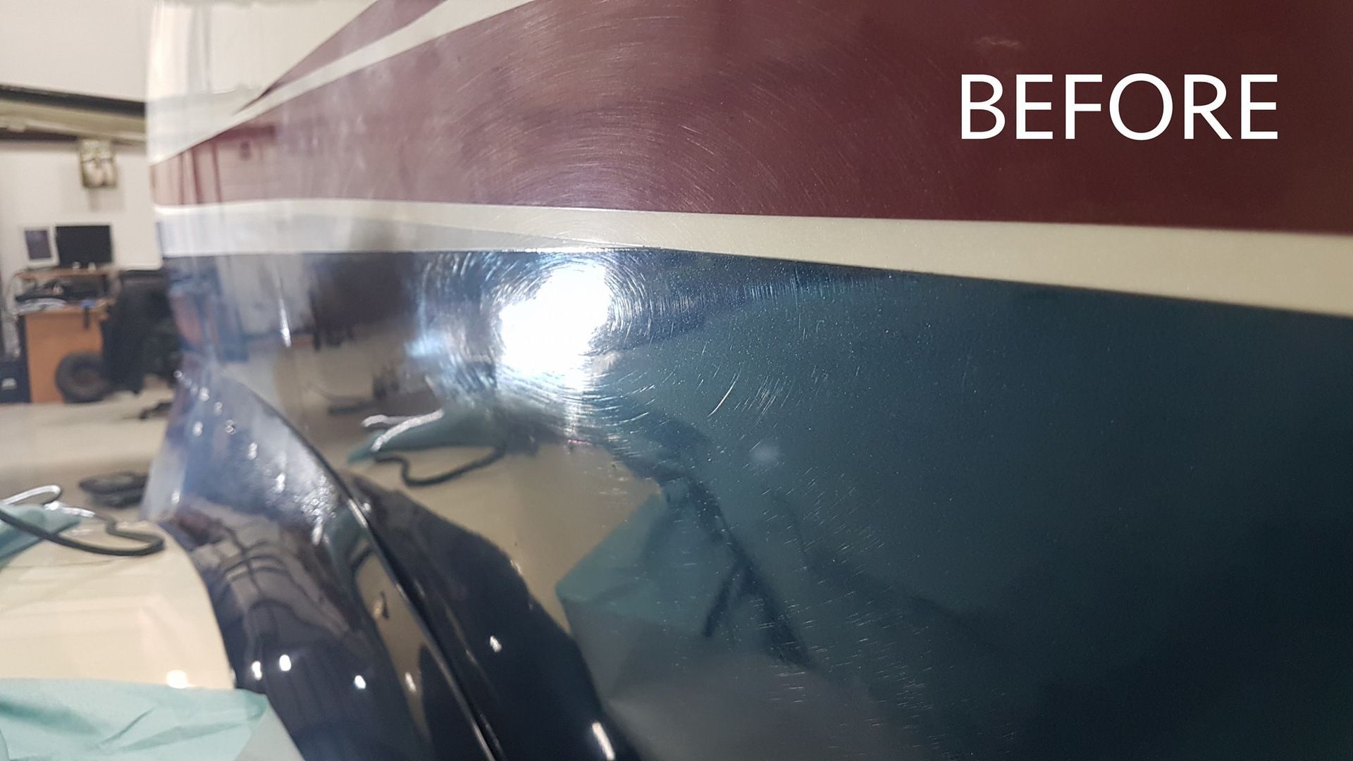 Close-up of a boat hull before repair with blue, white, and red painted sections.