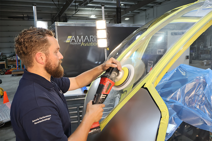 Man using a polisher on vehicle in a workshop.
