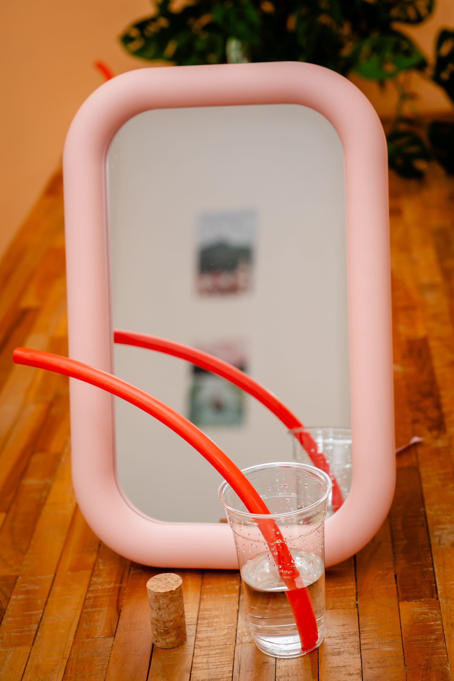 Woman holding a pink wavy mirror, reflecting her smiling image on a magenta background.