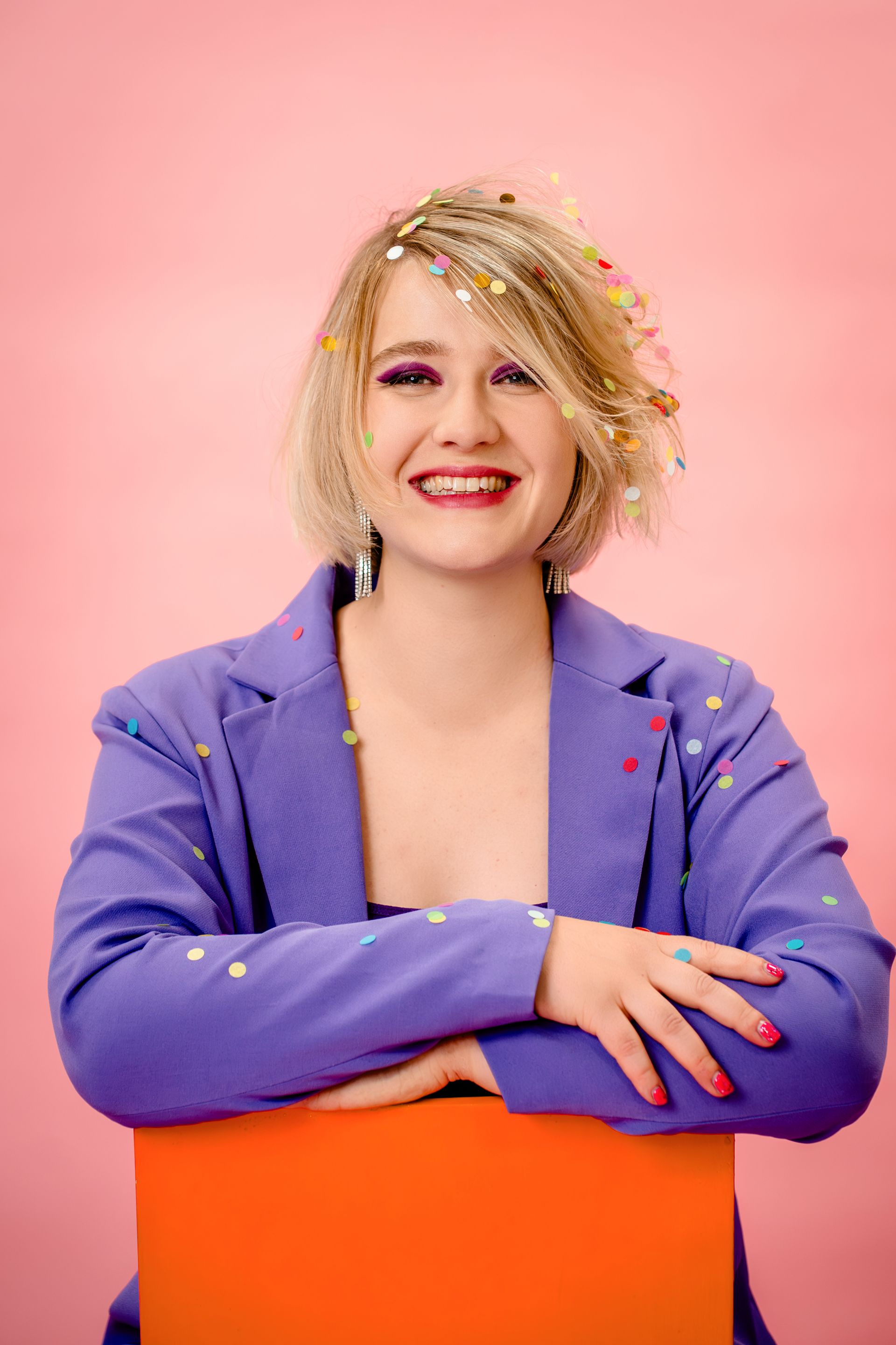 Woman holding a pink wavy mirror, reflecting her smiling image on a magenta background.