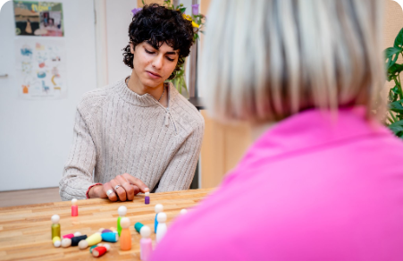 Two people playing a board game at a table, with colorful game pieces in the foreground