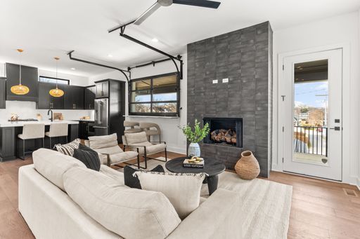 A living room with a couch , chairs , a fireplace and a ceiling fan.