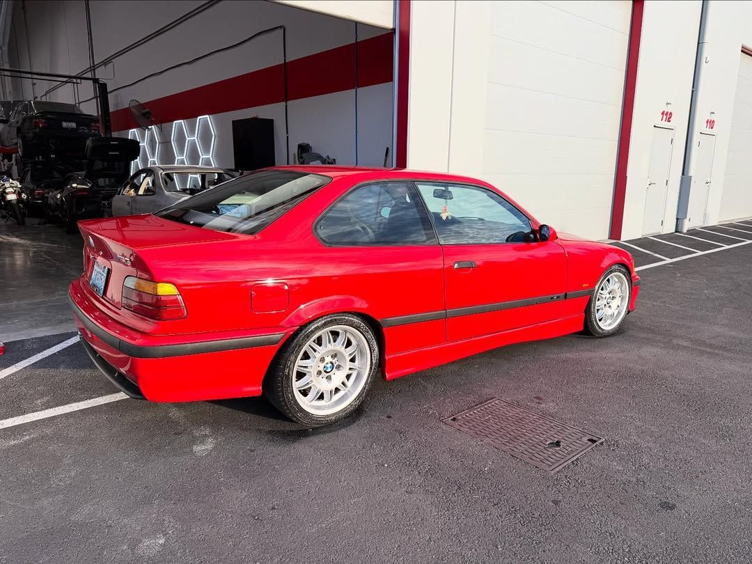 Red BMW coupe parked outside, with silver wheels.