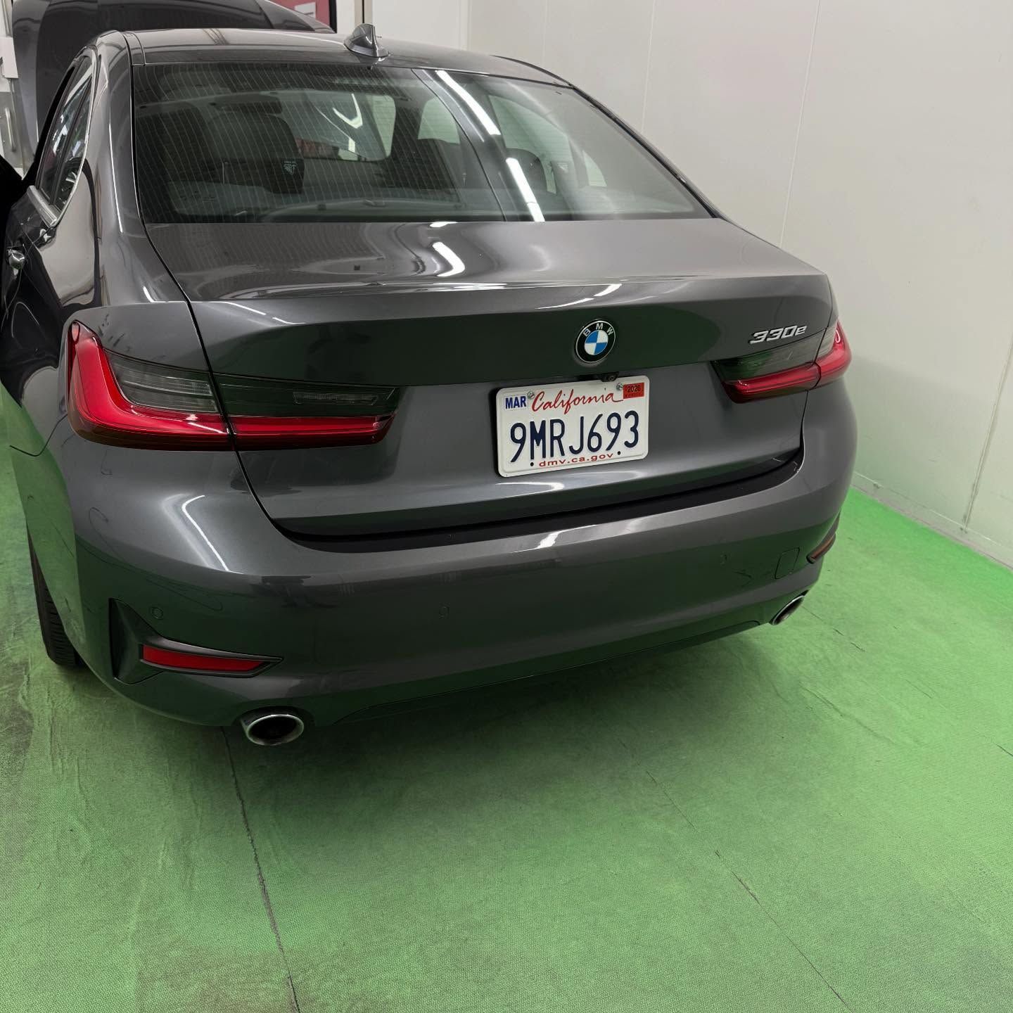A gray BMW sedan parked inside a garage; California license plate 9MRJ693.