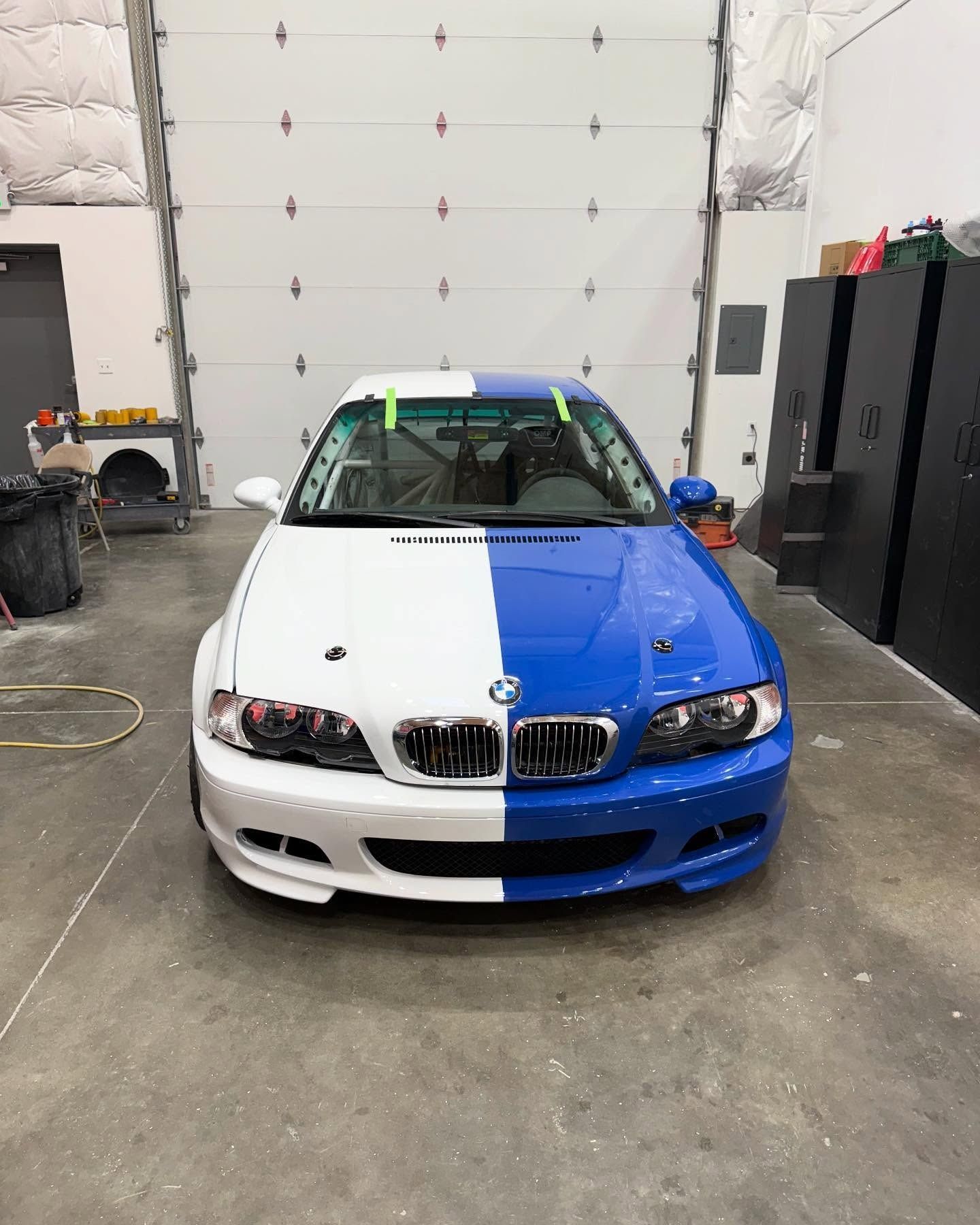 Two-tone BMW M3 car, white on left, blue on right, in a garage.