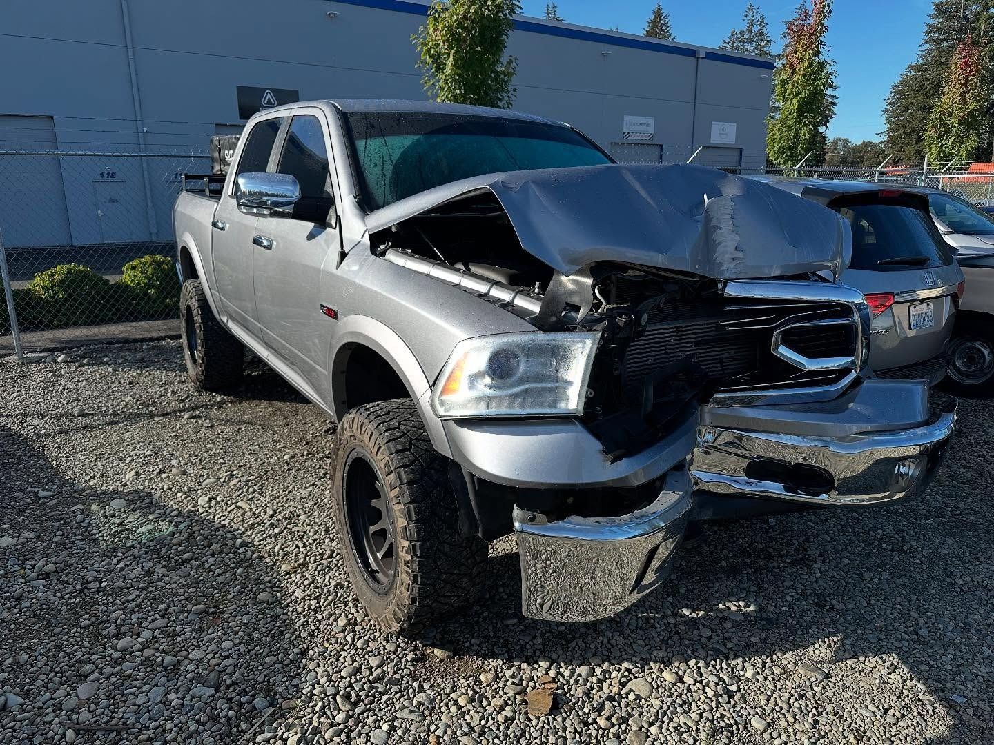 Gray Dodge Ram pickup truck with front-end collision damage in an outdoor setting.