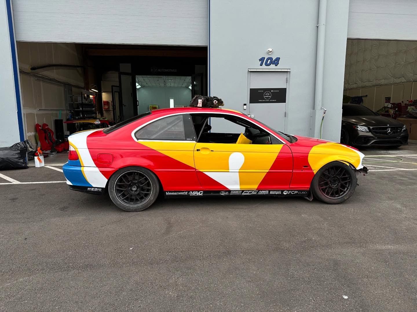 Colorful race car parked outside a building with garage doors.