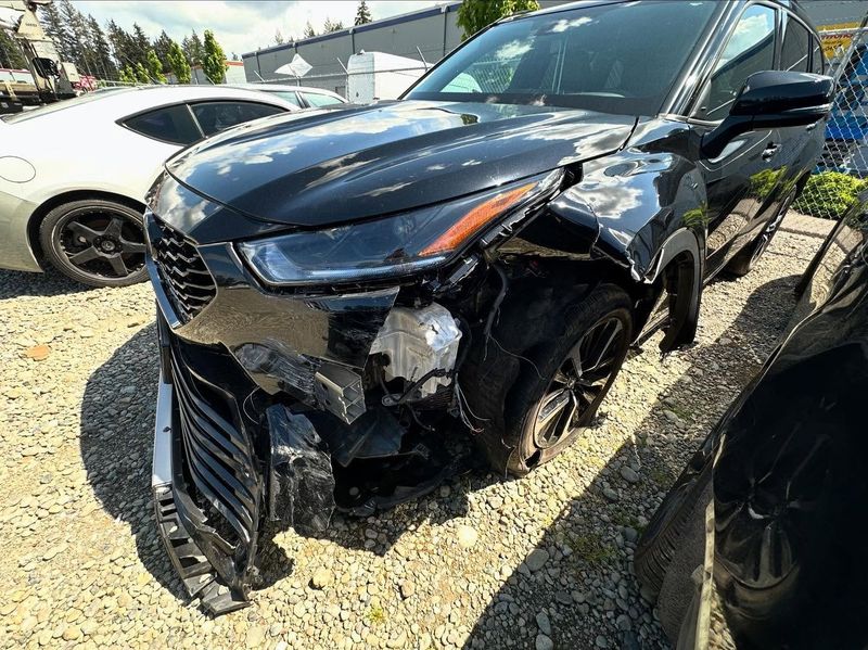 Black SUV with extensive front-end damage, including a crumpled fender and missing parts. Outdoors.