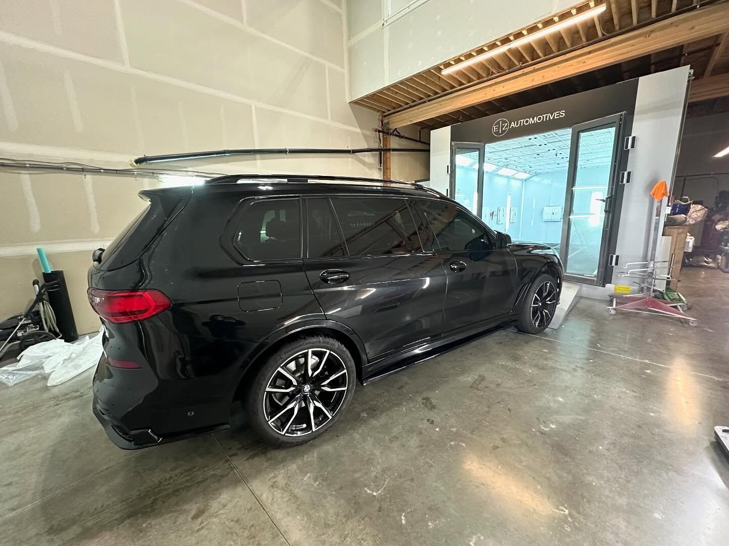Black SUV parked inside a garage; tinting bay in background.