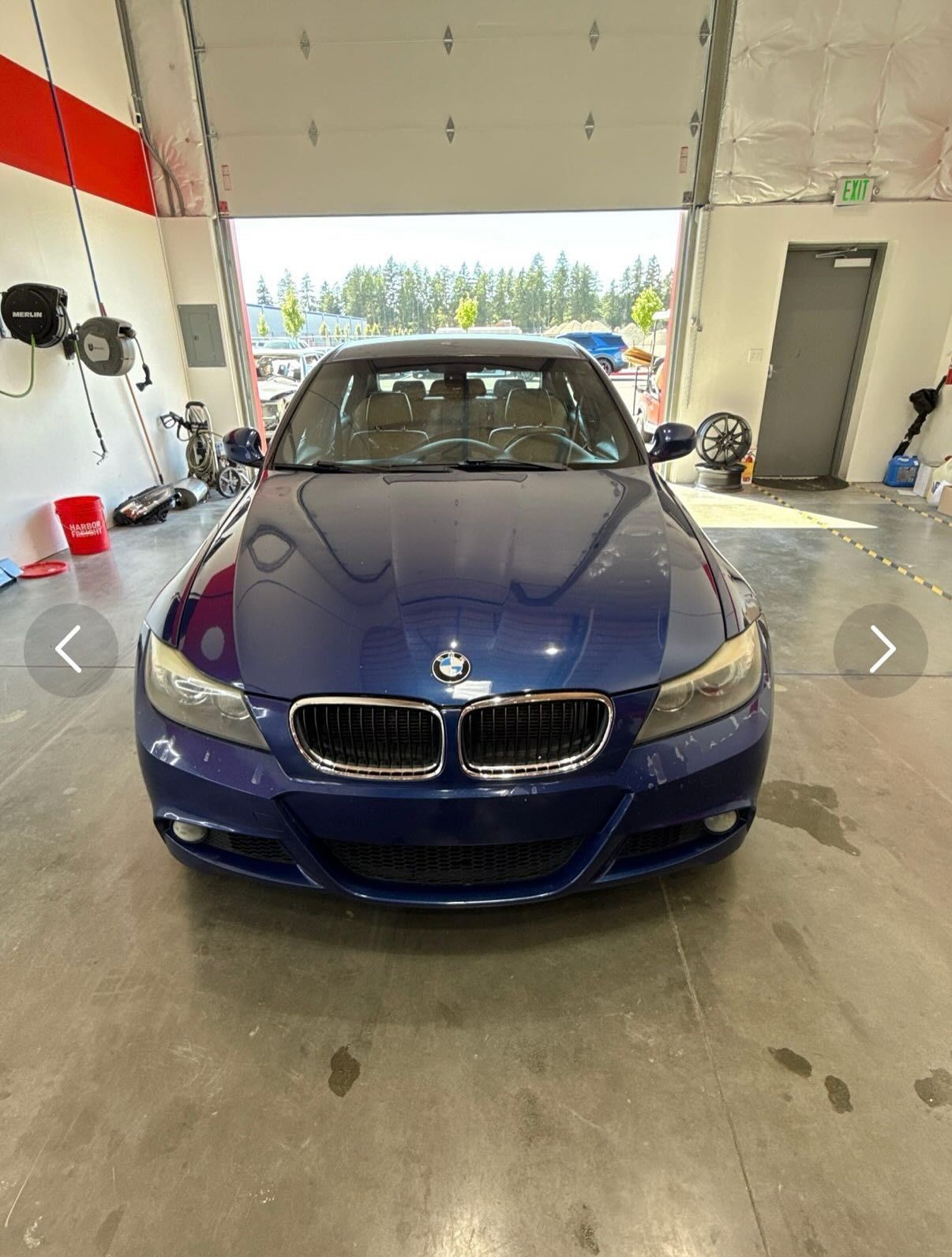 Blue BMW sedan in a garage with open door.