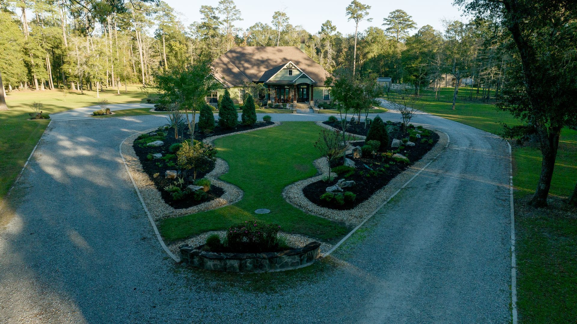 Circular driveway leading to a house with a landscaped island and surrounding trees