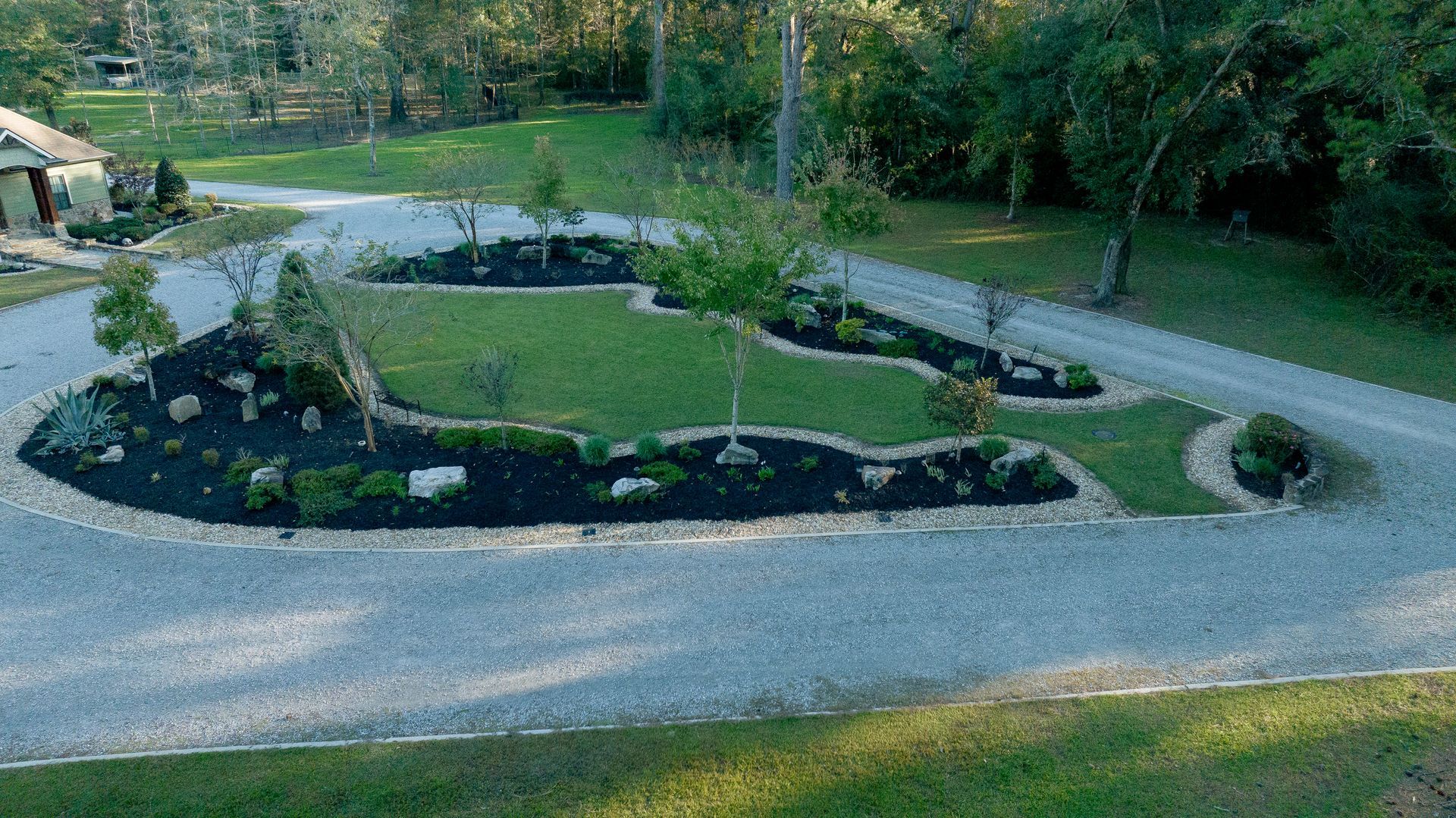 Curved gravel path around a landscaped garden bed with rocks and shrubs in a park.