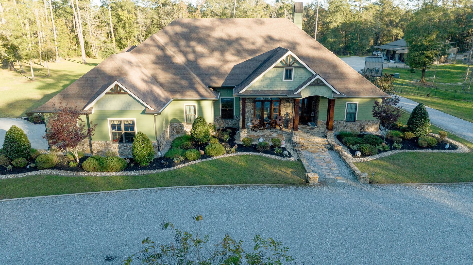 A  house with a brown roof, front porch, and landscaped yard.