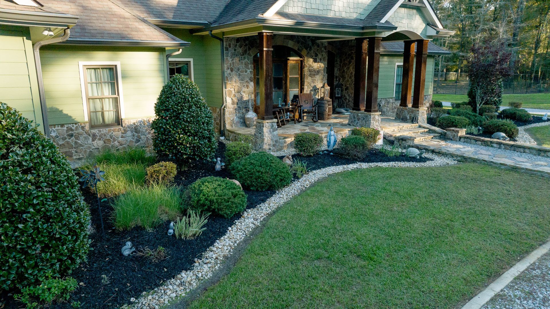 House with stone walkway, green lawn, and neatly trimmed shrubs in front yard