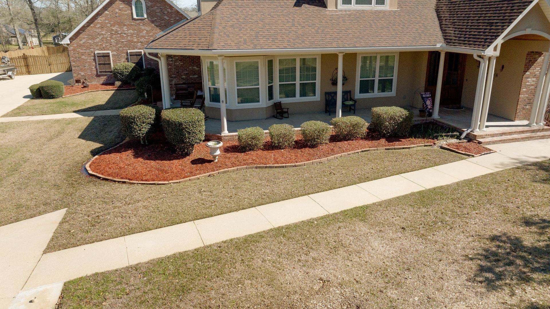 Suburban house with a front porch, landscaped shrubs, and a curved sidewalk leading to the entrance