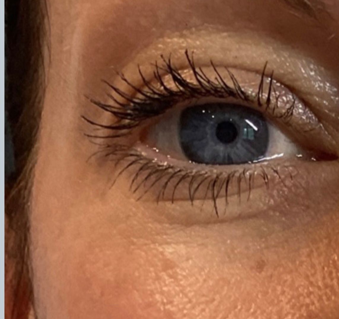 Close-up of a blue eye with long, dark eyelashes. Light skin.