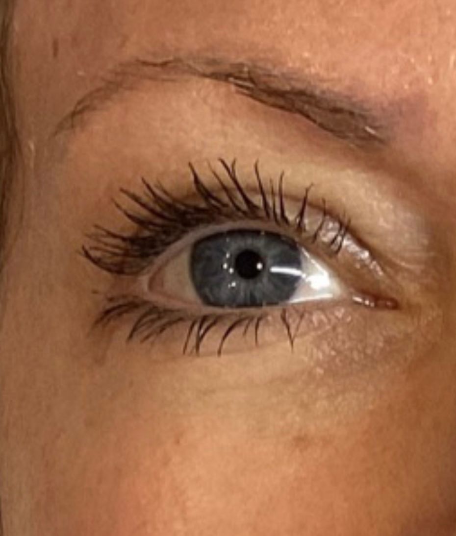 Blue eye with mascara, visible lashes, and a light-colored eyebrow. Skin is visible around the eye.