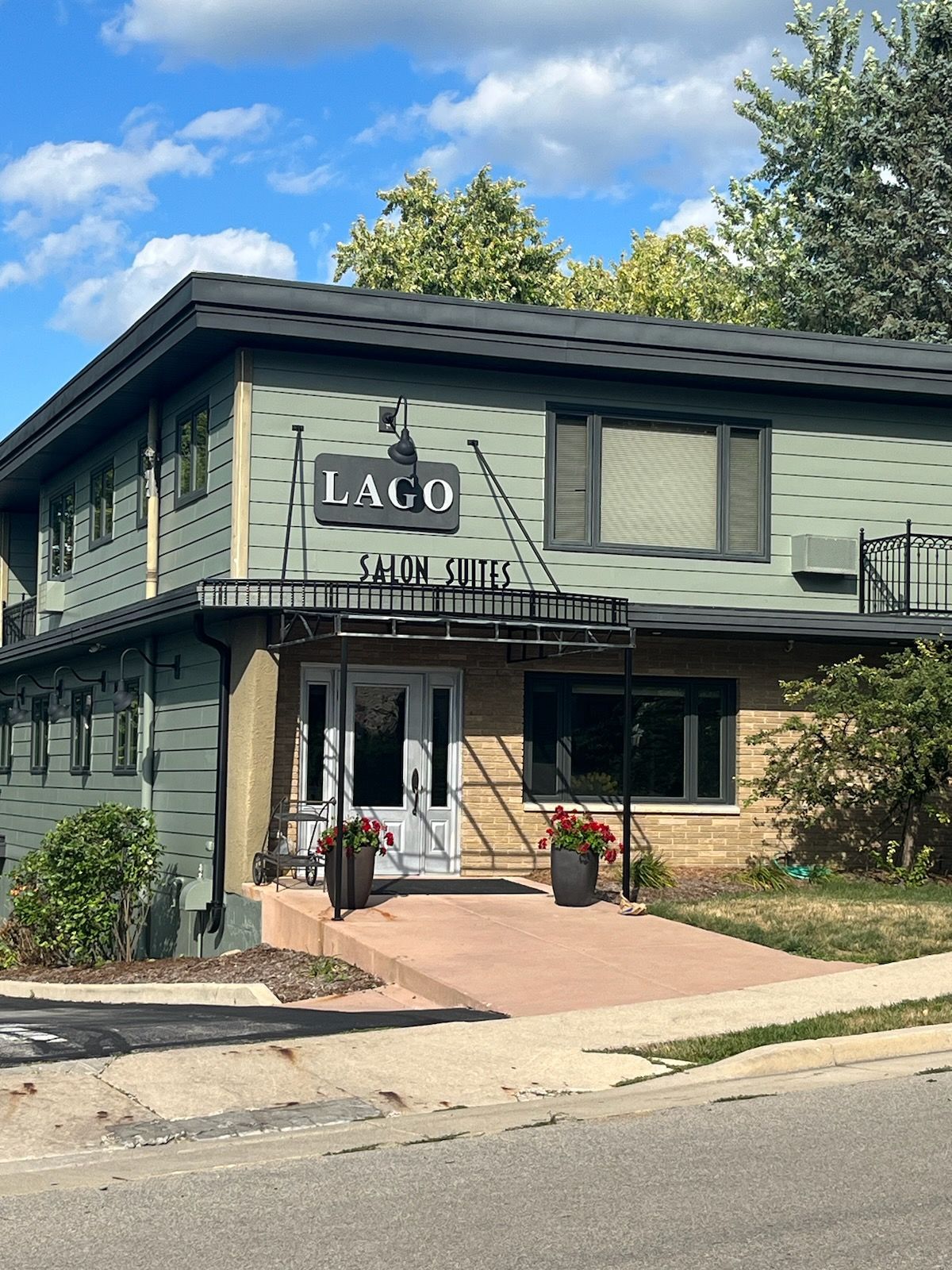 LAGO restaurant exterior with a green facade, black sign, and red flowers.