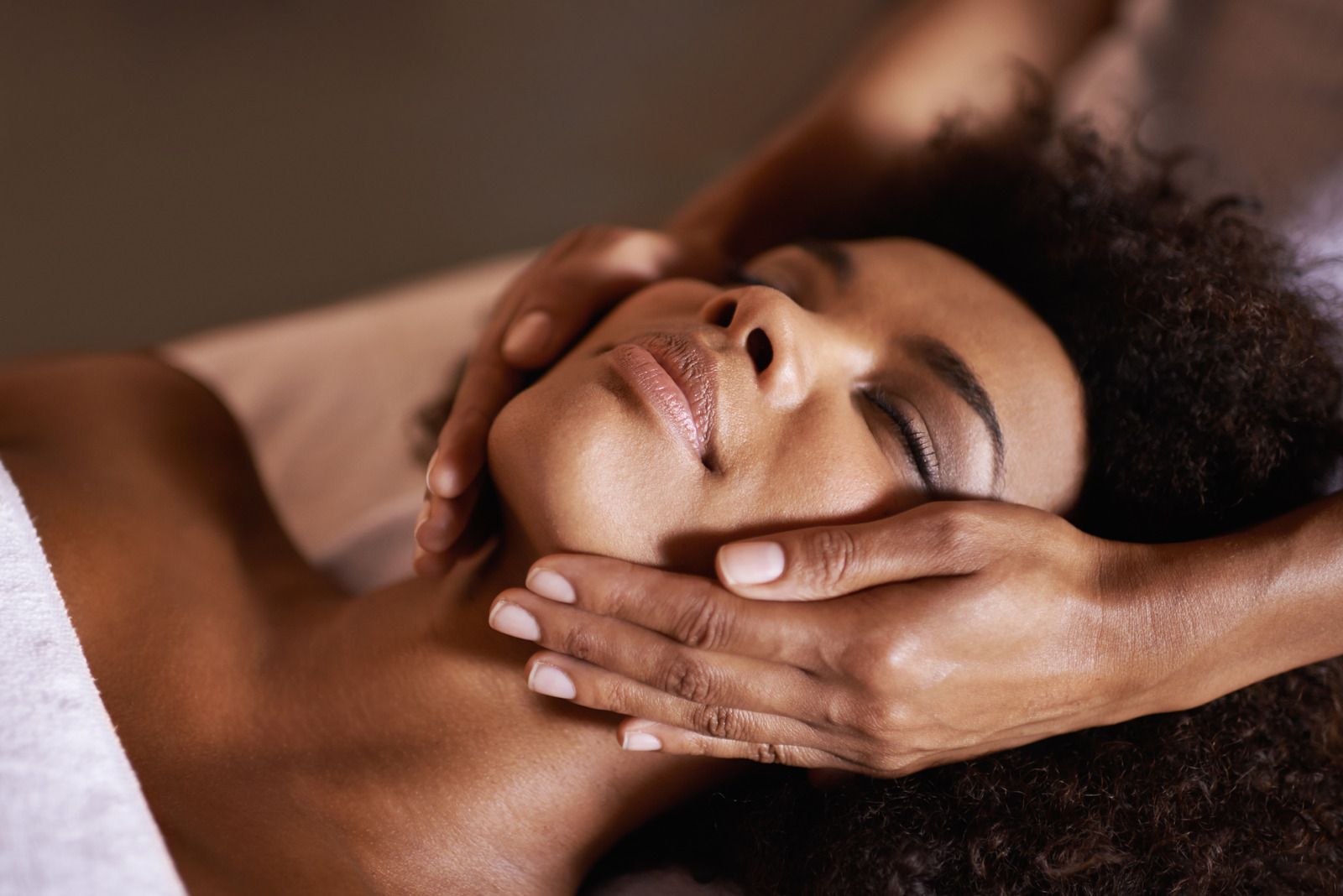 Person receiving facial massage; hands gently cradling face.