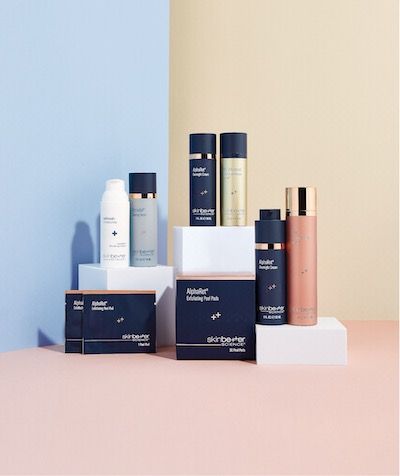 Cosmetics products displayed on white blocks against blue, peach, and beige backgrounds.