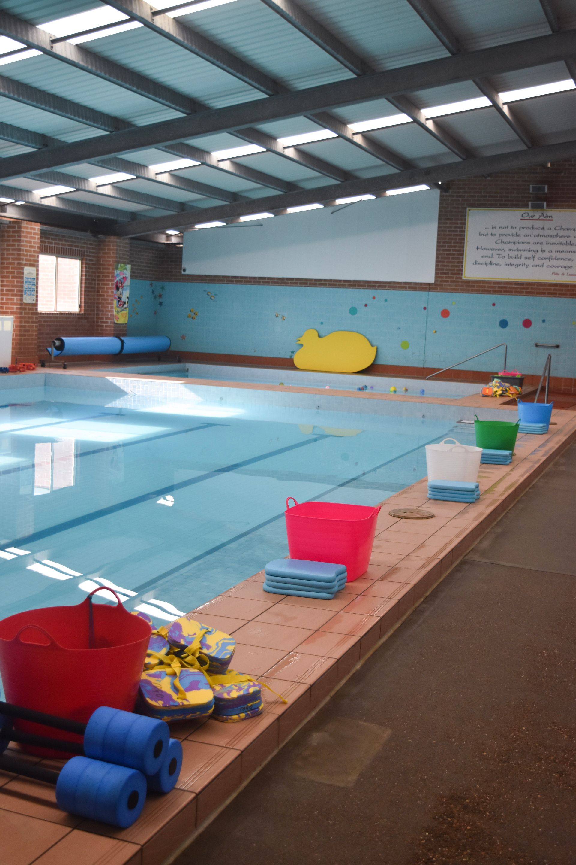 A large indoor swimming pool with buckets and floats on the edge.