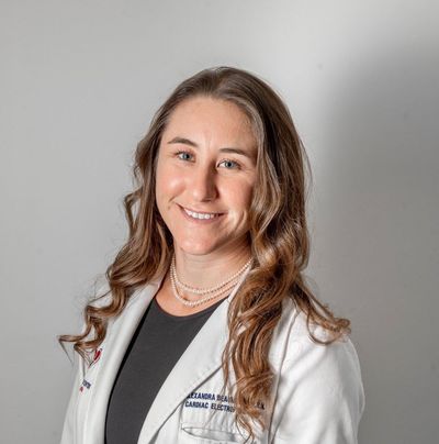Smiling medical professional in a white coat against a gray background