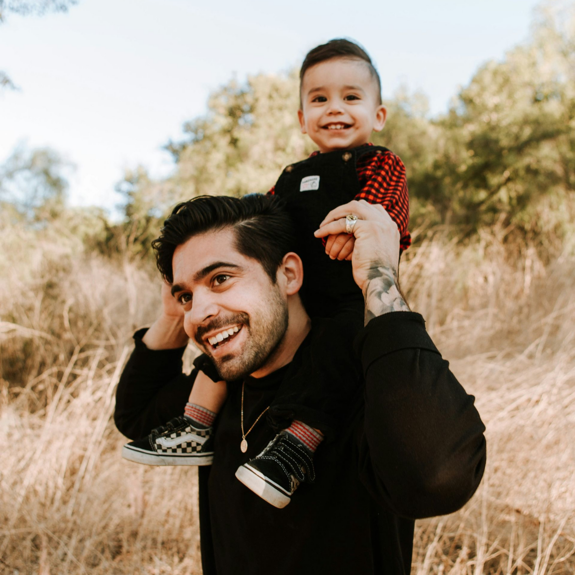 Hispanic father with son on shoulders smiling